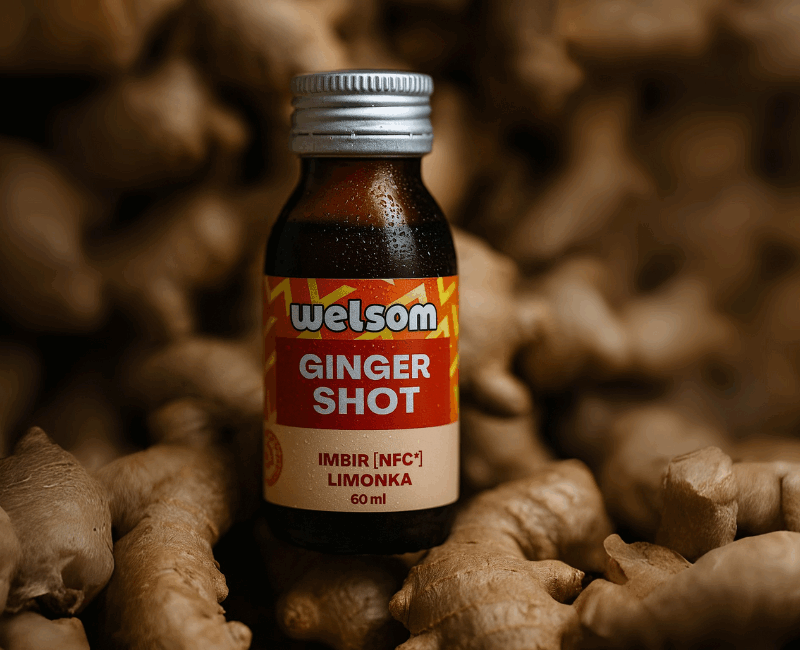 Butelka Ginger Shot Welsom stojąca pomiędzy kłączami imbiru.