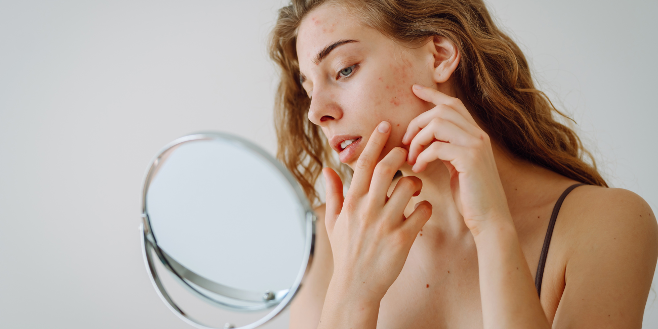 Kobieta ogląda swoją twarz w lustrze – presja idealnego wyglądu w social mediach